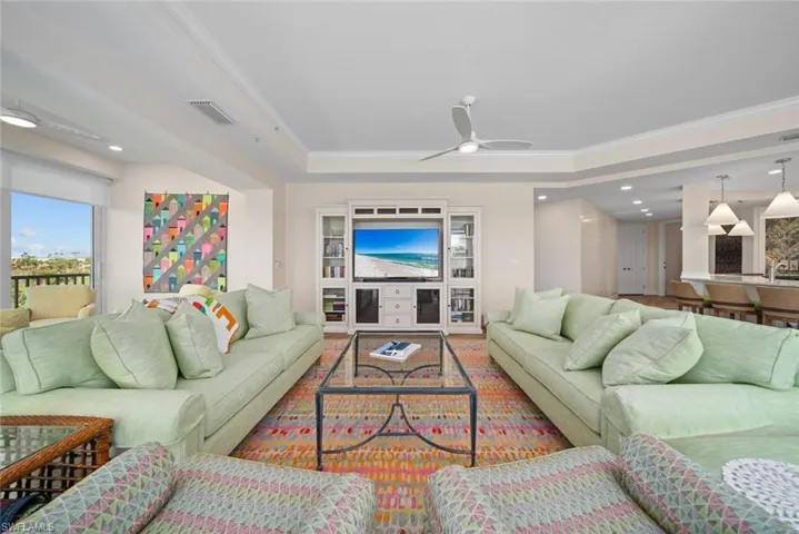 Living room featuring a tray ceiling, ceiling fan, and crown molding