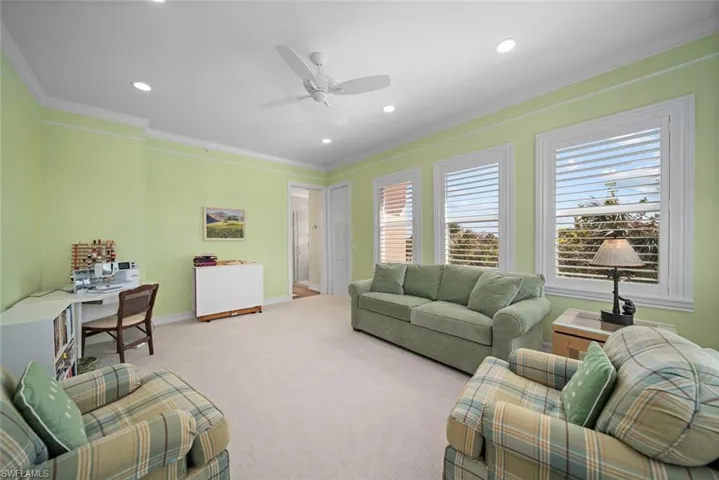 Living room featuring light colored carpet, ceiling fan, and crown molding