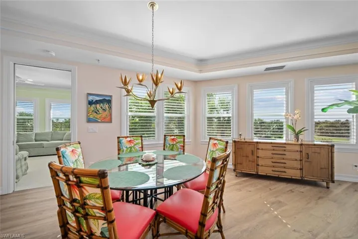 Dining area featuring a raised ceiling, light hardwood / wood-style flooring, and crown molding
