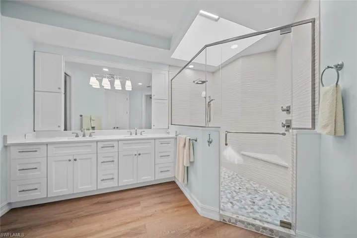 Bathroom featuring a shower with door, vanity, and wood-type flooring