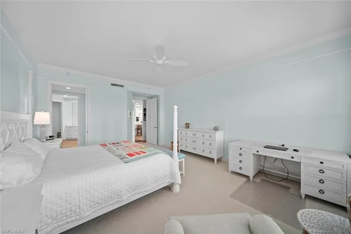Bedroom featuring ceiling fan, crown molding, and light carpet