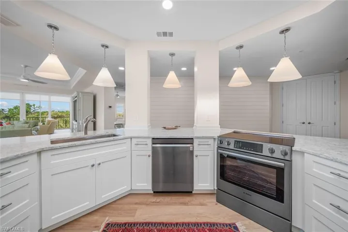 Kitchen with pendant lighting, white cabinets, stainless steel appliances, and sink