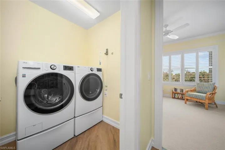 Laundry area with wood-type flooring, washer and clothes dryer, ornamental molding, and ceiling fan