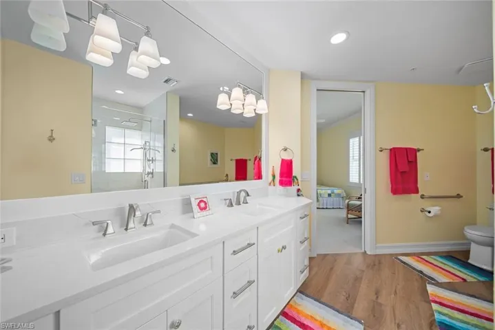 Bathroom featuring hardwood / wood-style floors, vanity, walk in shower, and a wealth of natural light