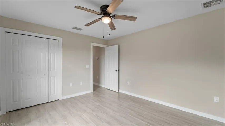 Unfurnished bedroom with baseboards, visible vents, light wood-style flooring, and a closet
