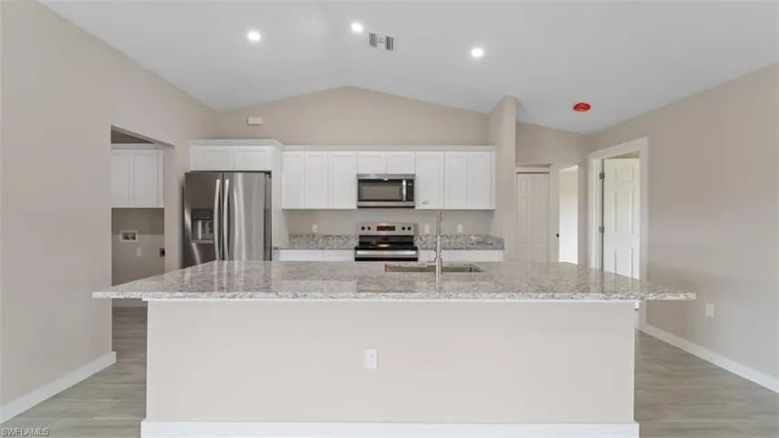 Kitchen featuring white cabinets, a kitchen island with sink, visible vents, and stainless steel appliances