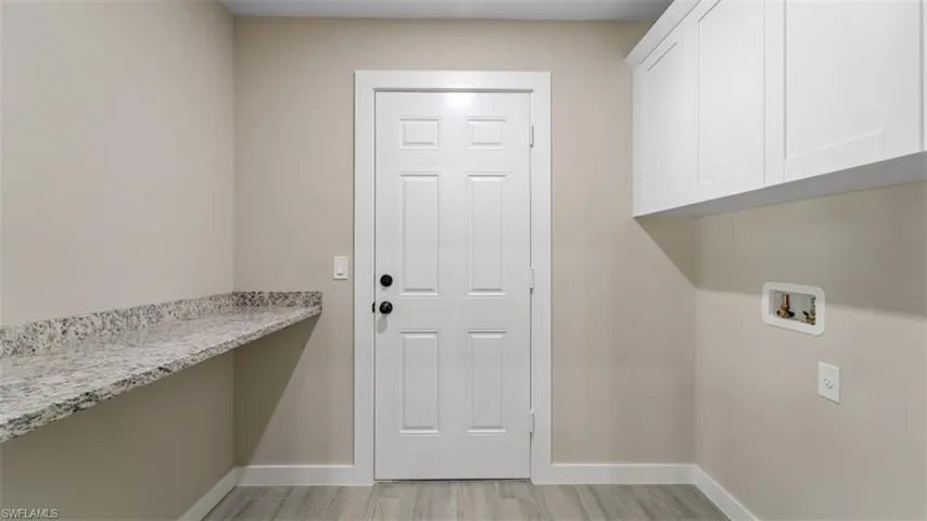 Washroom featuring cabinet space, baseboards, washer hookup, and light wood-style floors