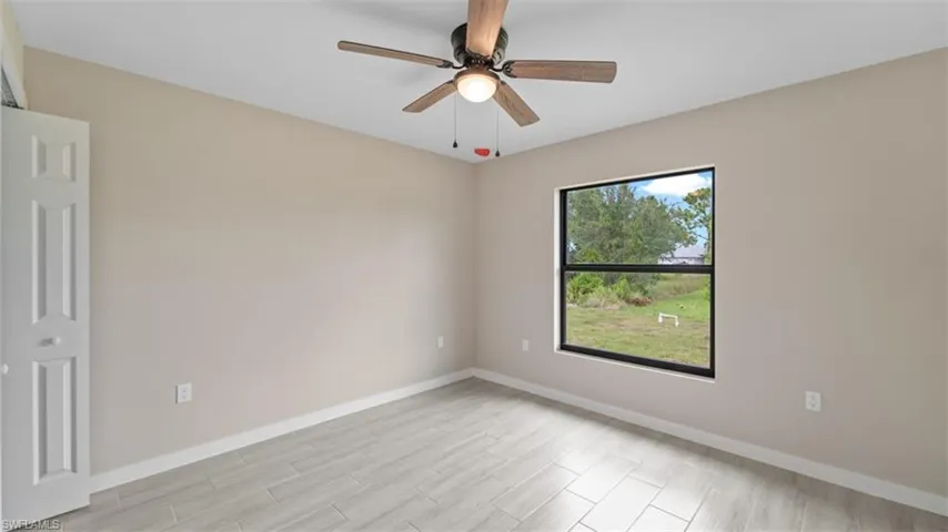 Spare room with ceiling fan, light wood-style floors, and baseboards