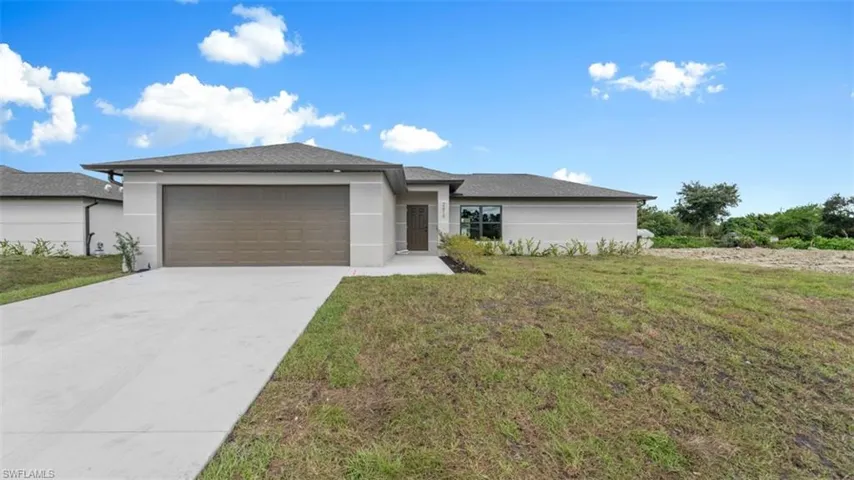 Prairie-style house featuring driveway, stucco siding, an attached garage, and a front yard