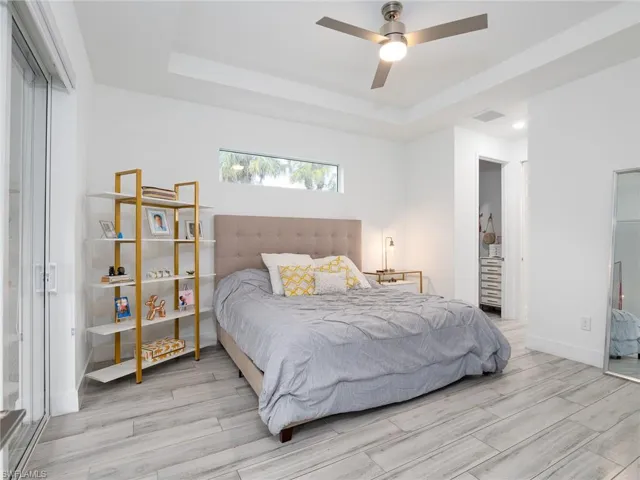 Bedroom featuring visible vents, a tray ceiling, baseboards, and wood finished floors
