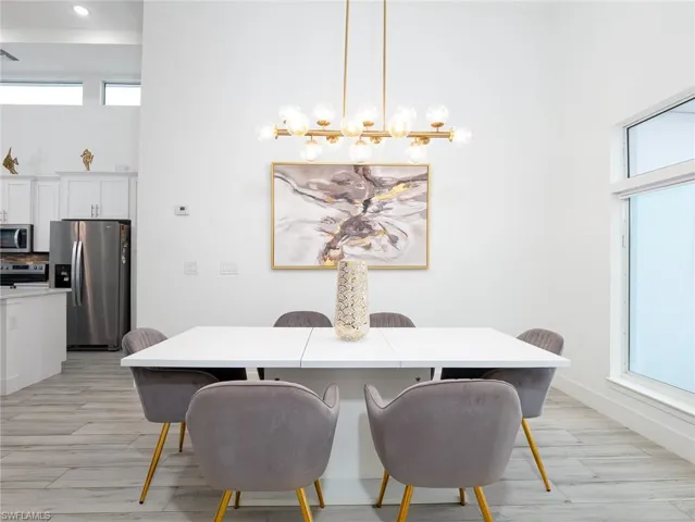 Dining space featuring light wood-style floors, a towering ceiling, and baseboards
