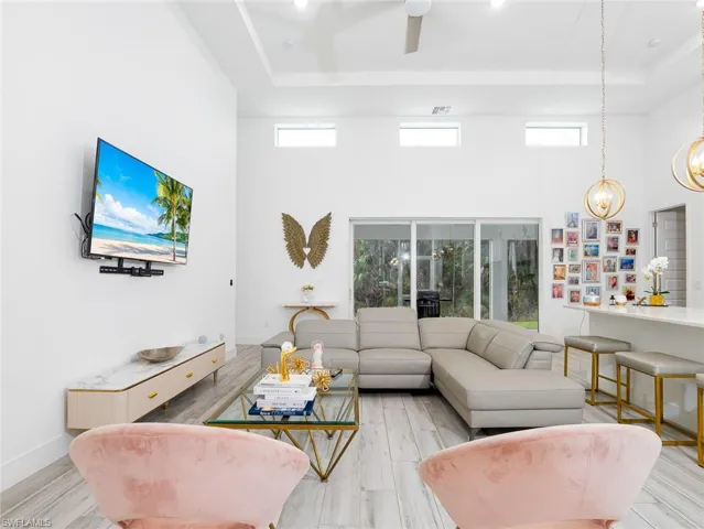 Living room featuring a tray ceiling, baseboards, light wood finished floors, and a towering ceiling