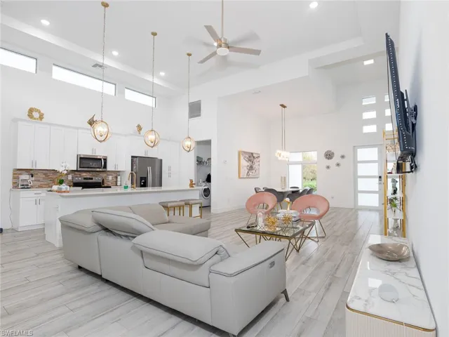 Living area featuring light wood finished floors, a towering ceiling, a ceiling fan, and visible vents