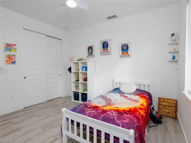 Bedroom with a closet, a ceiling fan, visible vents, wood finished floors, and baseboards
