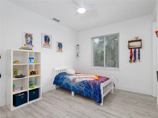 Bedroom with visible vents, light wood-style flooring, a ceiling fan, and baseboards