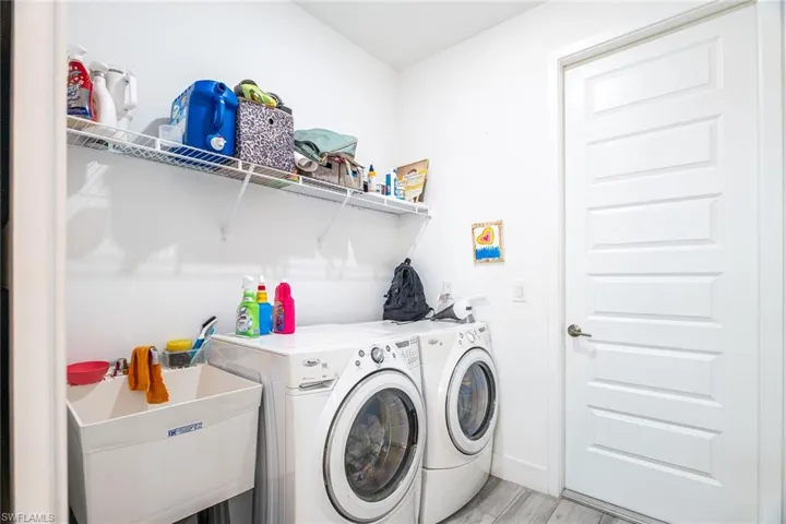 Laundry area featuring separate washer and dryer, baseboards, light wood-style flooring, laundry area, and a sink