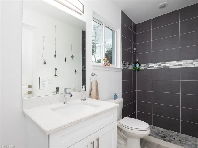 Full bathroom featuring vanity, a tile shower, and toilet