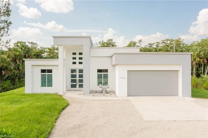 View of front of house with concrete driveway, a front yard, stucco siding, and an attached garage