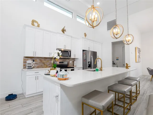 Kitchen featuring a chandelier, light countertops, a sink, stainless steel appliances, and backsplash