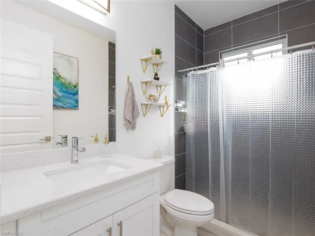 Full bathroom with curtained shower, vanity, and toilet