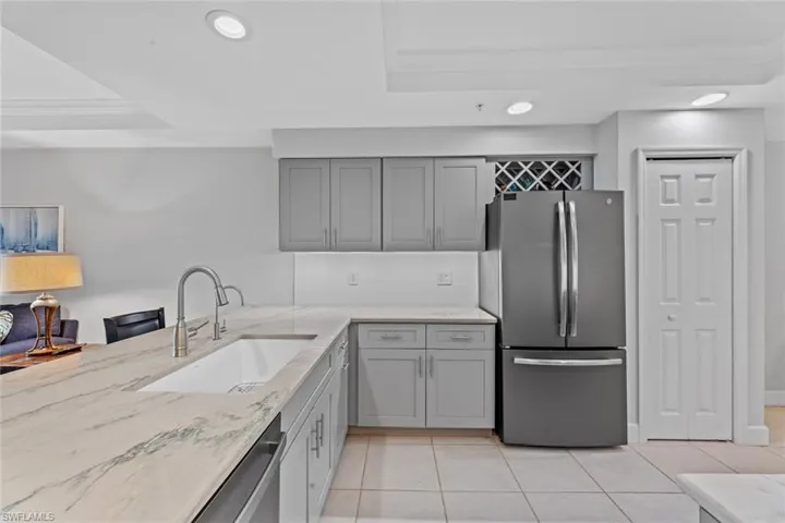 Kitchen with light tile patterned flooring, a tray ceiling, decorative backsplash, sink, and appliances with stainless steel finishes