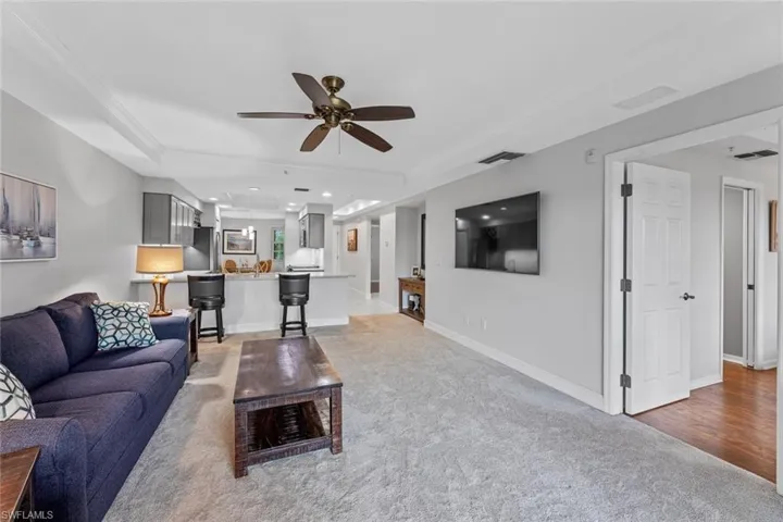 Living room with a tray ceiling, carpet floors, and ceiling fan