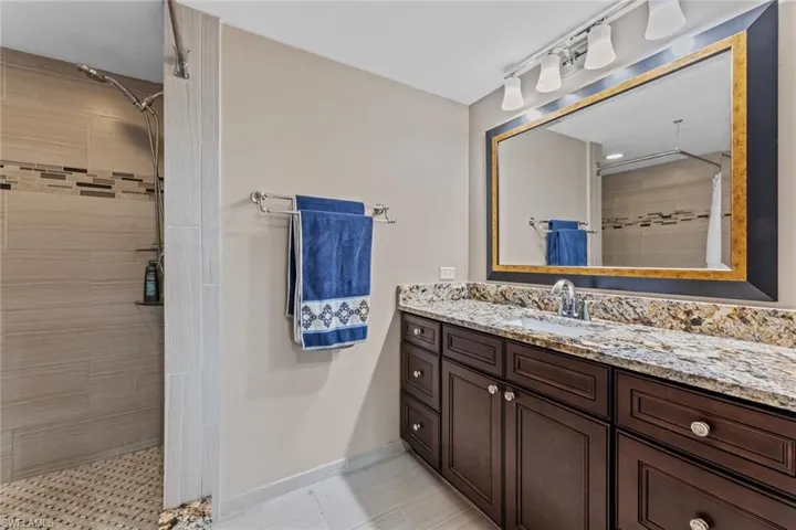 Bathroom with vanity, tile patterned flooring, and tiled shower
