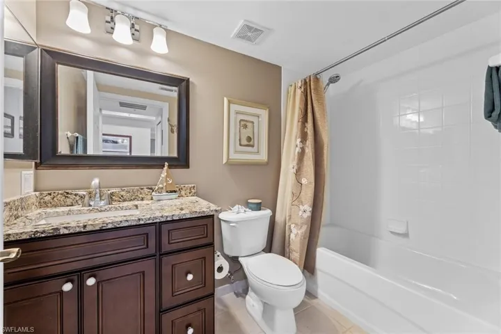 Full bathroom featuring tile patterned flooring, shower / bath combo, toilet, and vanity