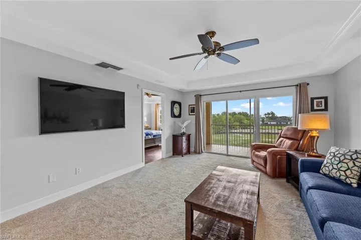 Living room featuring carpet floors, ceiling fan, and a tray ceiling