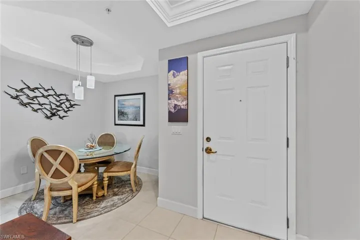 Dining space with light tile patterned floors and a raised ceiling