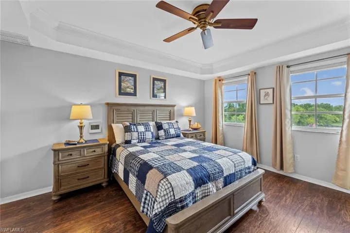 Bedroom with ceiling fan, dark hardwood / wood-style floors, a tray ceiling, and ornamental molding