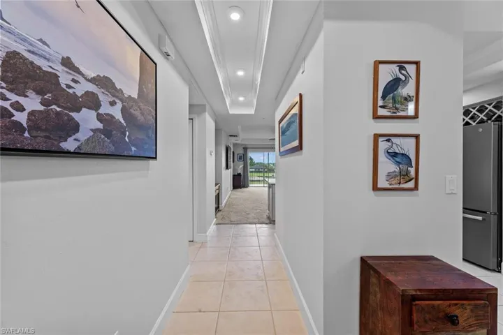 Corridor with light colored carpet and a tray ceiling