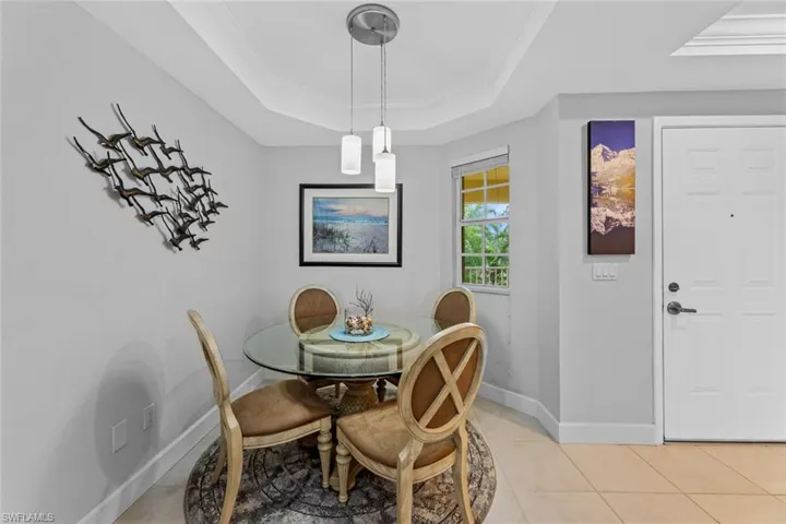 Dining room featuring light tile patterned flooring, crown molding, and a tray ceiling