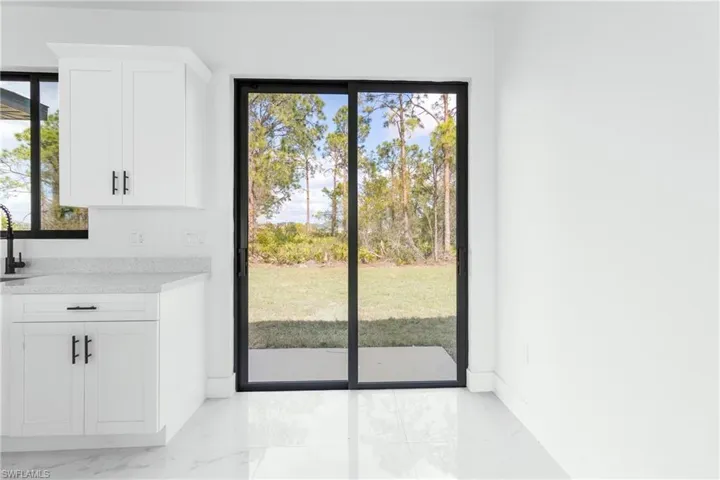 Doorway to outside featuring marble look tile flooring and baseboards