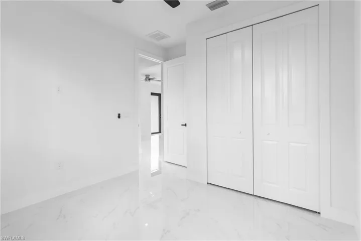 Unfurnished bedroom featuring light marble finish flooring, a ceiling fan, and a closet