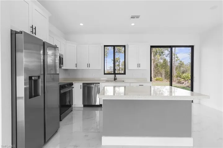 Kitchen with light marble finish flooring, stainless steel appliances, light stone countertops, and recessed lighting