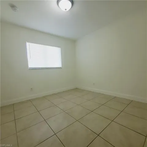 Unfurnished room with light tile patterned flooring and a smoke detector
