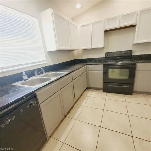 Kitchen featuring black appliances, light tile patterned floors, gray cabinetry, recessed lighting, and white cabinetry