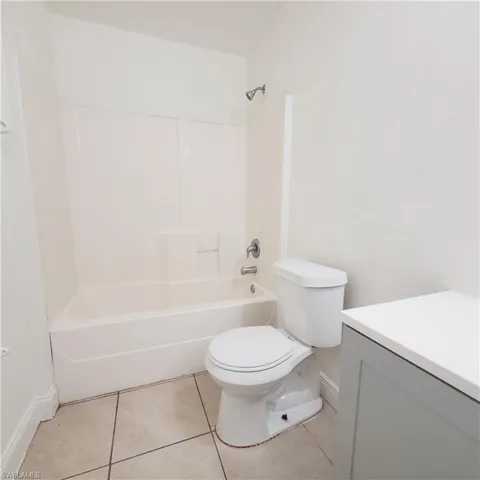 Full bath with light tile patterned floors, vanity, and bathtub / shower combination