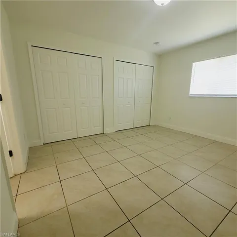 Unfurnished bedroom with light tile patterned floors and two closets