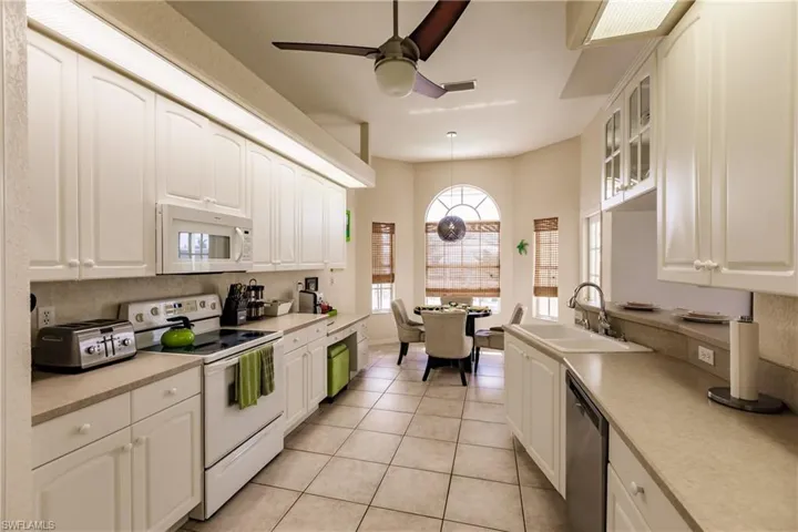 Kitchen featuring white appliances, ceiling fan, sink, pendant lighting, and light tile patterned floors