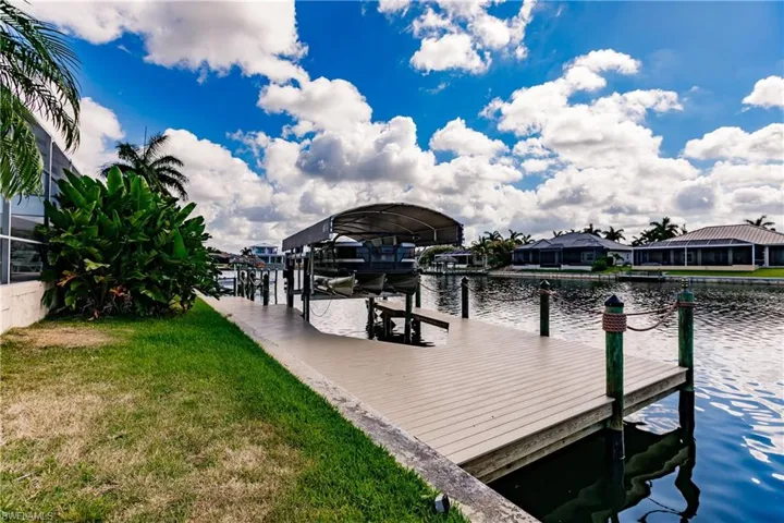 View of dock with a lawn and a water view