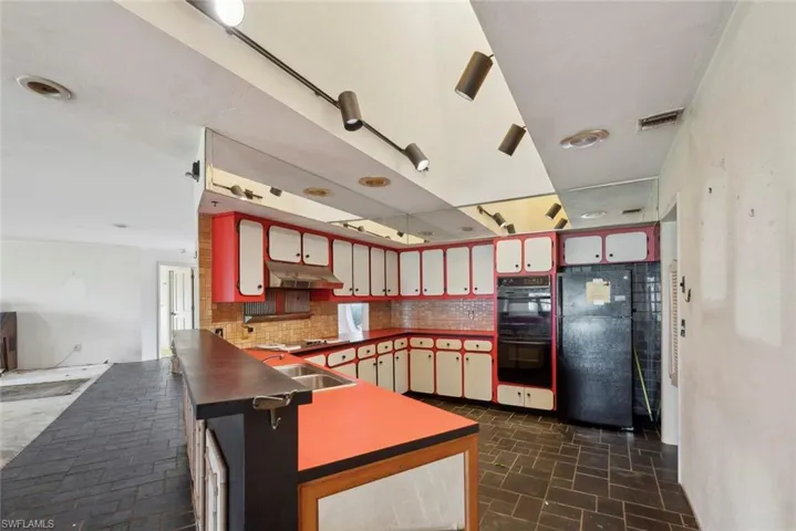 Kitchen featuring sink, black appliances, dark tile patterned flooring, and tasteful backsplash