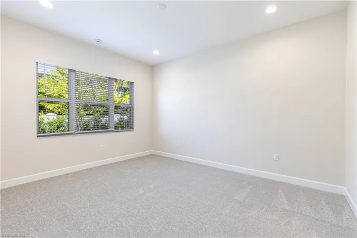 Empty room with light colored carpet and recessed lighting