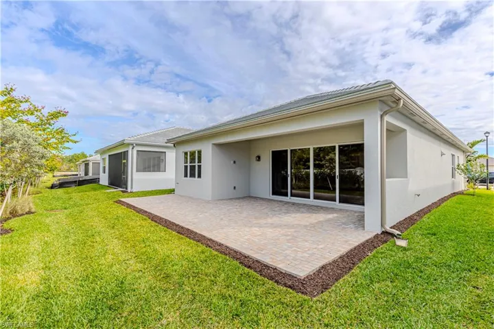 Back of house with a yard, stucco siding, a patio area, and a sunroom