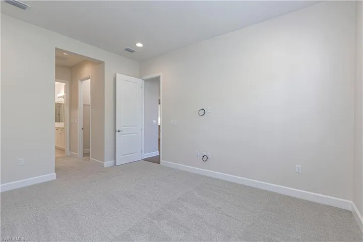 Unfurnished bedroom featuring light colored carpet, ensuite bath, and recessed lighting