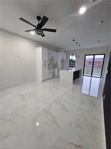 Unfurnished living room featuring recessed lighting, light marble finish flooring, and ceiling fan