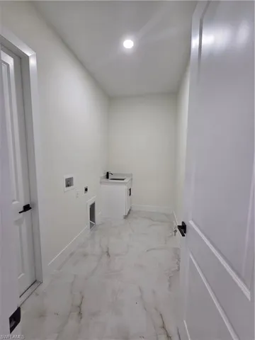 Laundry room with hookup for an electric dryer, light marble finish floors, and washer hookup