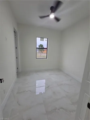Unfurnished room featuring light marble finish flooring and a ceiling fan