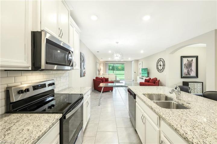 The kitchen, with island, features neutral granite countertops and subway tile backsplash.